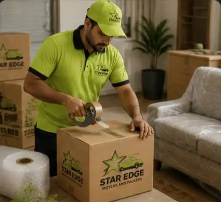 Star Edge mover taping a branded box beside a wrapped sofa